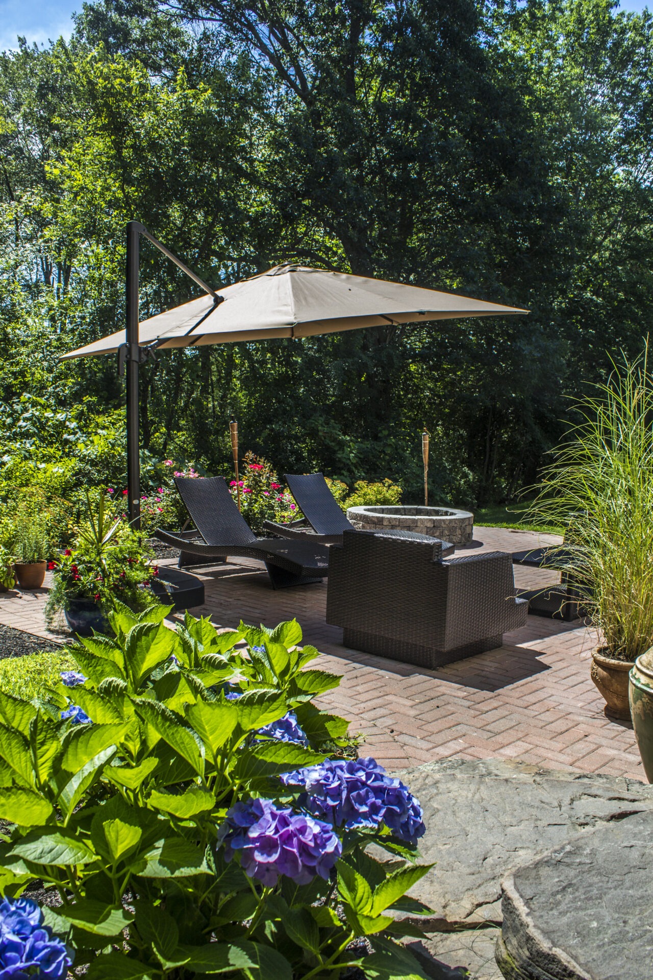 A tranquil garden scene with lounge chairs, umbrella, and vibrant flowers amidst lush greenery. Perfect for relaxation and enjoying nature.