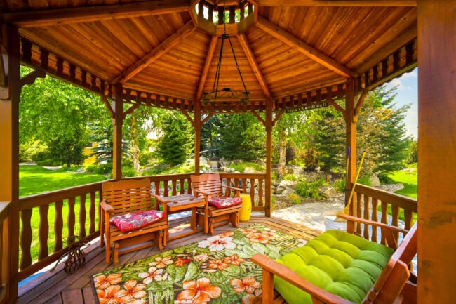 Backyard landscaping ideas using a gazebo, outdoor seating, and a beautiful surrounding wooded area.