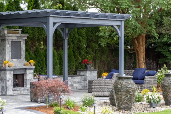 Backyard landscaping ideas using a pergola and stone patio.