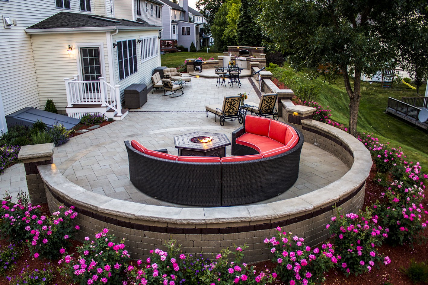 A circular backyard seating area with surrounding flowers.